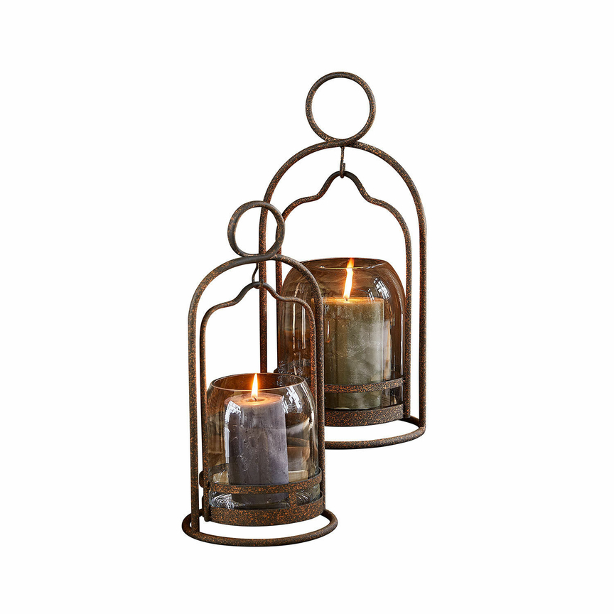 Set aus zwei rostfarbenen Metall-Glas-Laternen mit brennenden Dekokerzen für gemütliche Atmosphäre